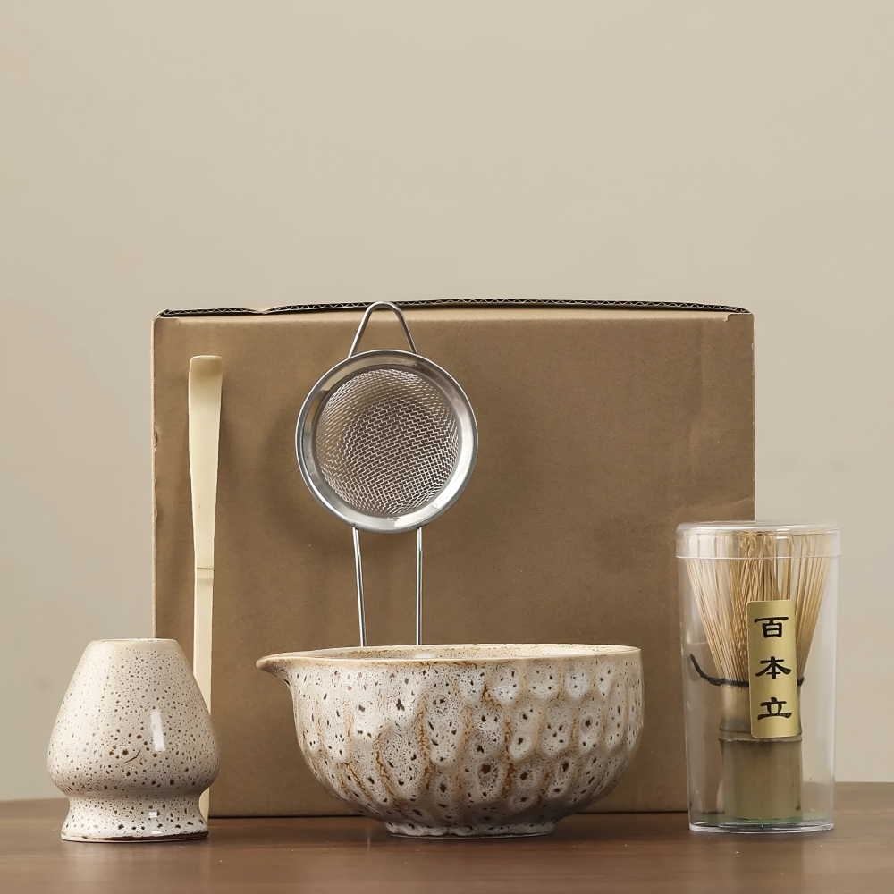 5-teiliges Matcha-Set in cremeweißer Glasur mit braunen Sprenkeln vor einem braunen Versandkarton