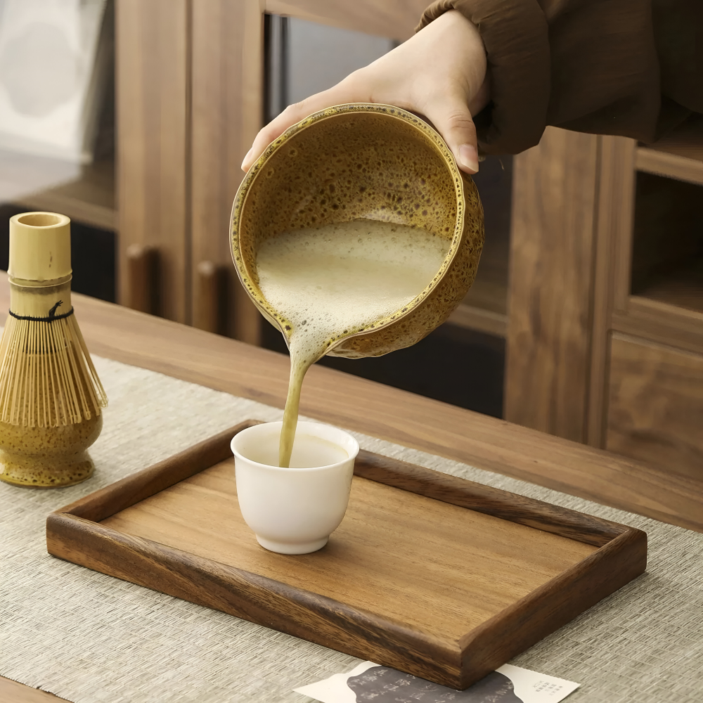 5-teiliges Matcha-Set mit aufgeschäumtem Matchatee und gelber Schale beim Ausgießen