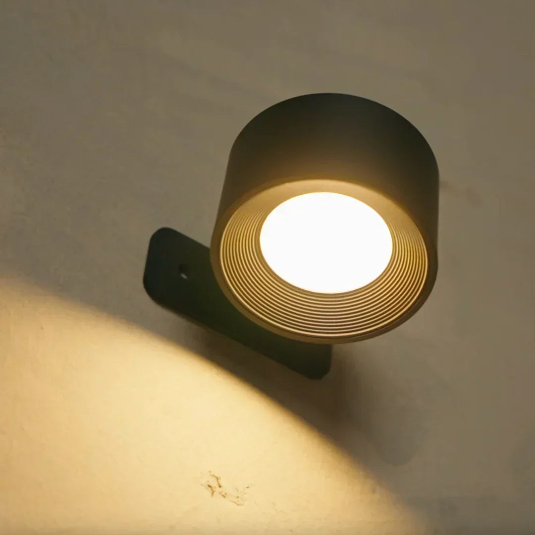 Schwarze Wandleuchte von schräg unten, die einen warmen Lichtkegel an die Wand wirft 3