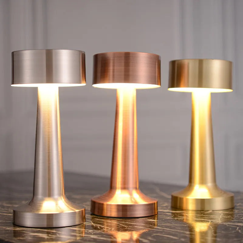 Drei LED-Tischlampen aus Metall in Silber, Kupfer und Gold auf Marmortisch, kabellos, Touch-Sensor.