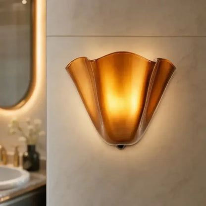Nahaufnahme der warm leuchtenden bernsteinfarbenen Wandlampe an einer Marmorwand.