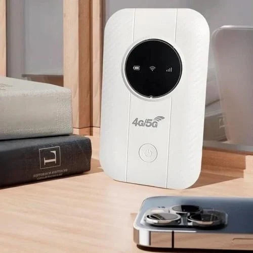 Weißer Router mit rundem schwarzem Display steht auf einem Holztisch neben Büchern und einem Smartphone 3