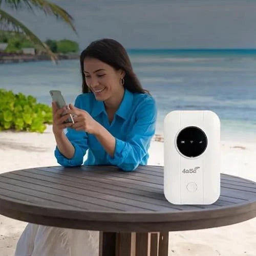 Frau mit Smartphone sitzt an einem Holztisch am Strand, daneben steht der weiße Router 6