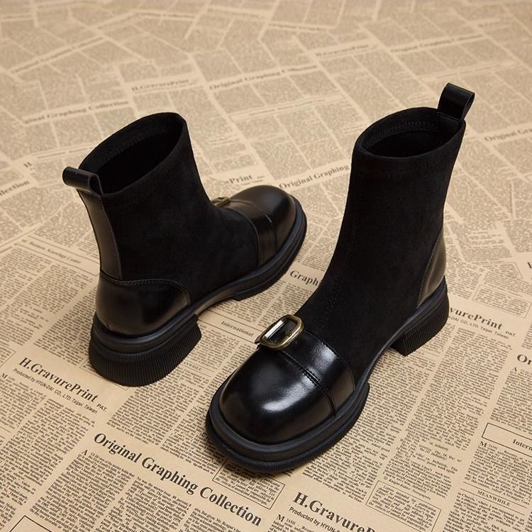 Schwarze Wildlederstiefel mit glänzender Lederkappe, goldfarbener Schnalle und Zuglasche, weitere Ansicht.