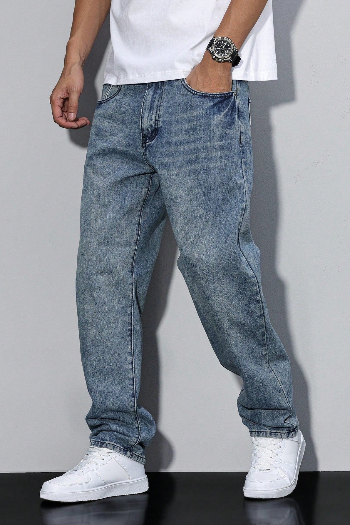 Seitlicher Look in einer mittelblau ausgewaschenen Variante der lockeren Jeans, kombiniert mit weißem Shirt und Sneakern 7