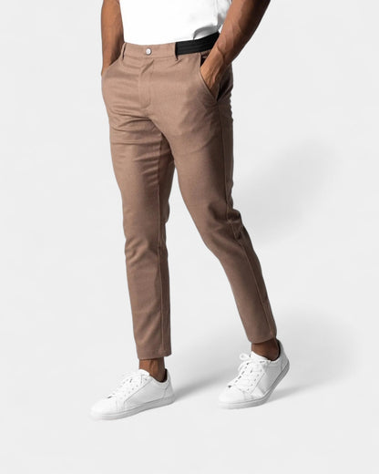 Model in der braunen Hose mit schwarzem Stretchbund, weißem Shirt und weißen Sneakern 5
