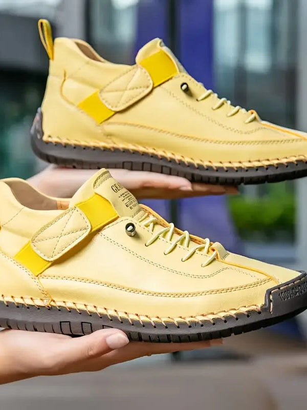 Gelbe Sneaker mit dunkler Sohle, von zwei Händen übereinander gehalten 15