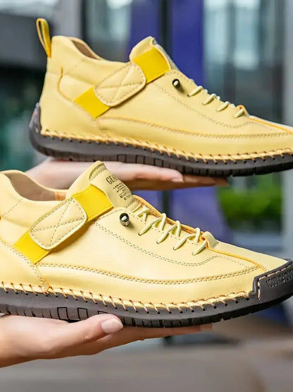 Gelbe Sneaker mit dunkler Sohle, von zwei Händen übereinander gehalten 15