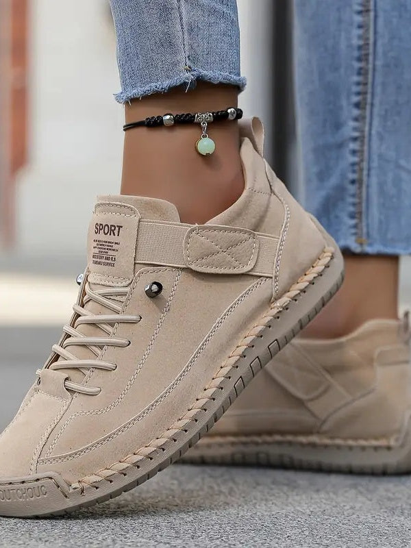 Beige Wildleder-Sneaker an den Füßen einer Frau, Nahaufnahme von Klettband und Zierstich 14