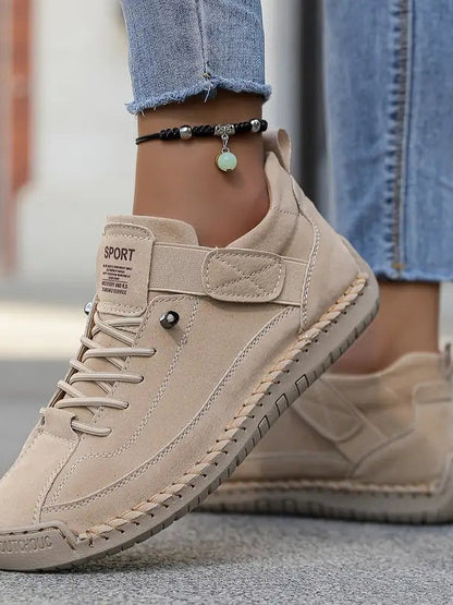 Beige Wildleder-Sneaker an den Füßen einer Frau, Nahaufnahme von Klettband und Zierstich 14