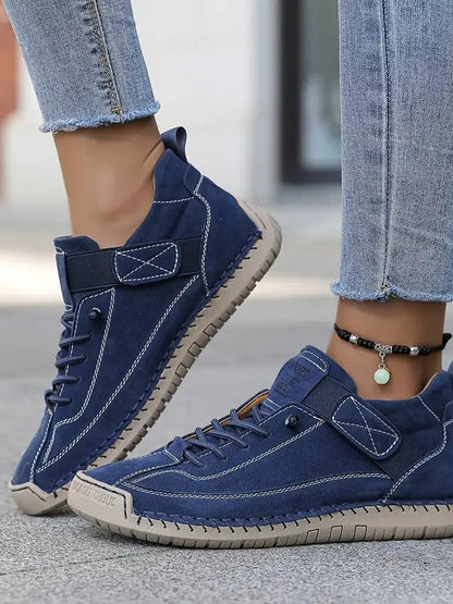 Blaue Sneaker an den Füßen einer Frau in Jeans, Draufsicht mit Klettband und heller Sohle 3