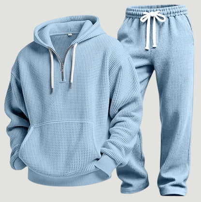 Hellblaues Waffelstrick-Set aus Hoodie mit halbem Reißverschluss und Jogginghose mit weißem Kordelzug, freigestellt nebeneinander. 6