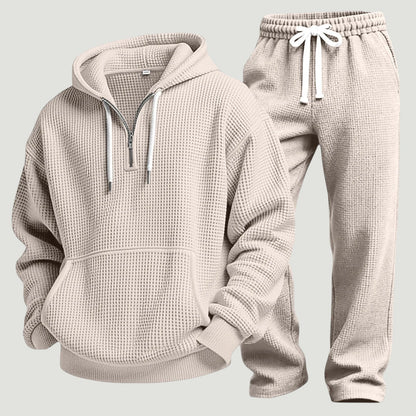 Beiges Waffelstrick-Set aus Hoodie mit halbem Reißverschluss und Jogginghose mit weißem Kordelzug, freigestellt nebeneinander. 8