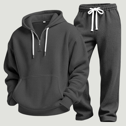 Dunkelgraues Waffelstrick-Set aus Hoodie mit Känguru-Tasche und Jogginghose mit weißem Kordelzug, freigestellt nebeneinander. 7