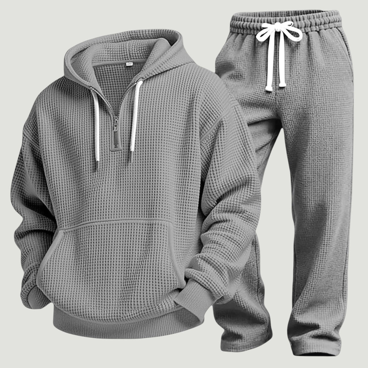 Graues Waffelstrick-Set aus Hoodie mit halbem Reißverschluss und Jogginghose mit weißem Kordelzug, freigestellt nebeneinander. 10