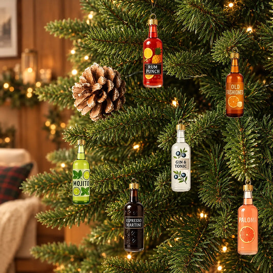 Sechs bunte Mini-Flaschen mit goldenen Kappen hängen an einem beleuchteten Tannenbaum neben einem Zapfen, im Hintergrund ein gemütliches Wohnzimmer. 1