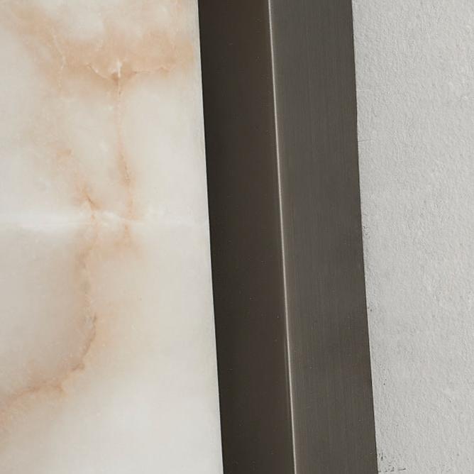 Nahaufnahme der Marmoroberfläche mit zarten rosafarbenen Adern neben der gebürsteten, kantigen Metallhalterung an einer hellen Wand. 25