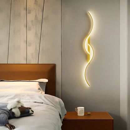 Goldfarbene Wellenlampe leuchtet im Schlafzimmer an der Wand über einem Nachttisch neben dem Bett 2