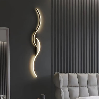 Schwarze Wellenlampe leuchtet an dunkelgrauer Wand neben einem grauen gesteppten Sofa 6