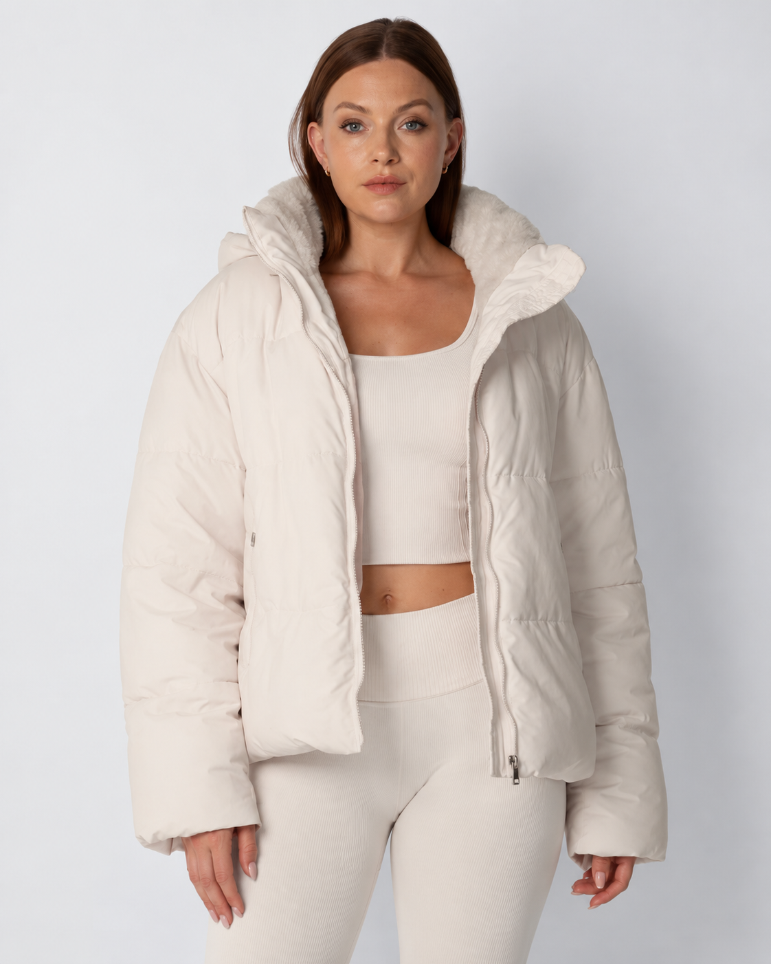 Model trägt die offene cremeweiße Steppjacke mit Fleecekragen zu hellem Crop-Top und Leggings, Frontansicht 1