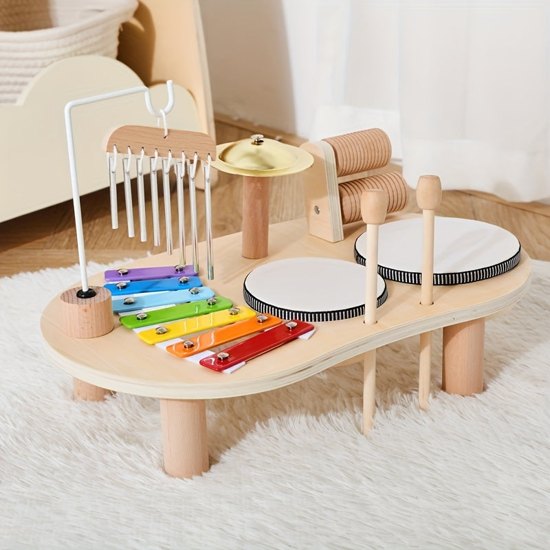 Musiktisch auf einem weißen Flauschteppich mit Klangspiel, Xylophon, Becken, Rassel und zwei Trommeln, die Schlägel stecken in den Haltelöchern. 6