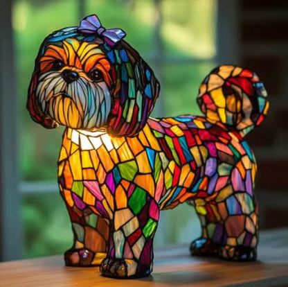 Kleine Hundefigur mit lila Schleife auf dem Kopf und buntem Mosaikkörper, steht auf einem Holztisch vor einem Fenster. 23