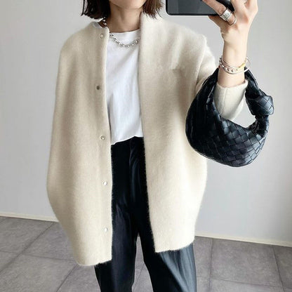Cremeweißer Cardigan mit Druckknöpfen und V-Ausschnitt, getragen mit schwarzer Hose und geflochtener Handtasche 2