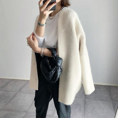 Cremeweißer Cardigan offen getragen, seitlich fotografiert, mit weißem Shirt, schwarzer Hose und kleiner schwarzer Tasche 3