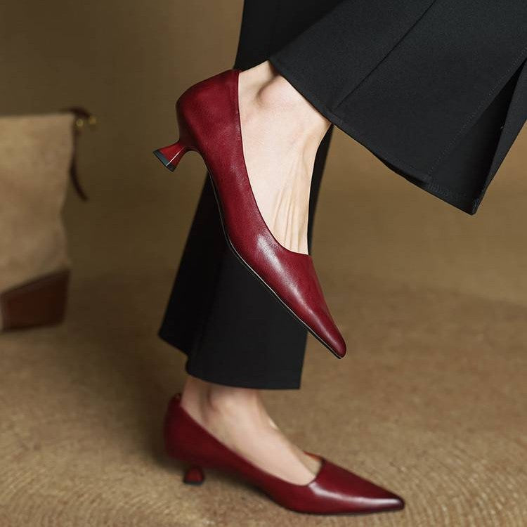 Model in weinroten Pumps und schwarzer weiter Hose, ein Fuß angehoben, Absatz und Seite sichtbar 9