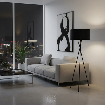 Schwarze Stehlampe mit Dreibeinfuß im Abendlicht neben grauem Sofa, abstraktem Bild und Zimmerpflanze 3