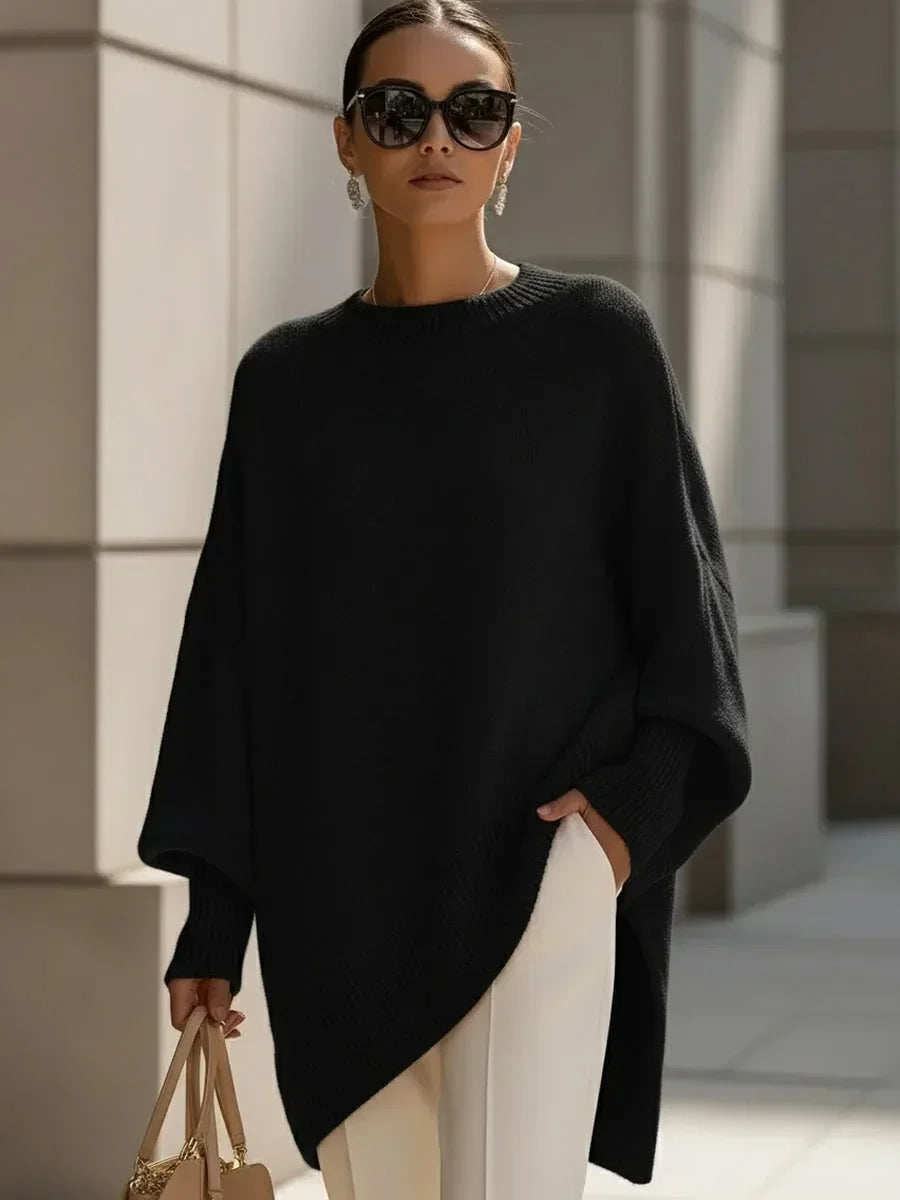 Schwarzer Oversize-Pullover mit Rippbündchen, vom Model mit Sonnenbrille, weißer Hose und heller Handtasche getragen. 6