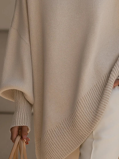 Detailaufnahme des gerippten, asymmetrisch verlaufenden Saums und des weiten Fledermausärmels mit Rippbündchen am beigen Pullover. 3