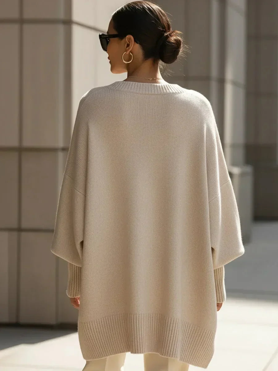 Rückansicht des beigen Oversize-Pullovers am Model mit Haarknoten, gerader Rippsaum und lockere Ärmel mit Bündchen. 4