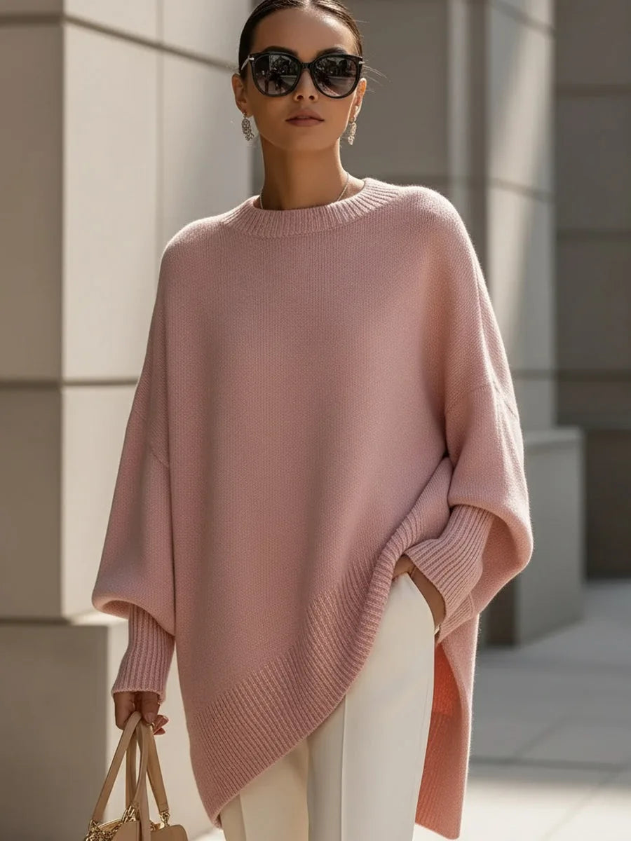 Rosafarbener Oversize-Pullover mit asymmetrischem Rippsaum, vom Model mit Sonnenbrille, weißer Hose und Handtasche getragen. 11