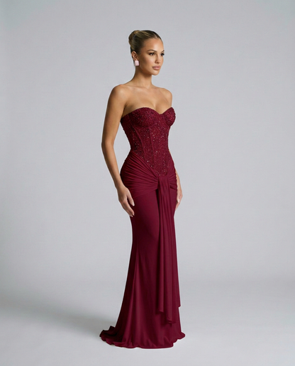 Weinrotes Kleid mit funkelnder Korsage in seitlicher Dreiviertelansicht, die Drapierung fällt an der Hüfte herab 4