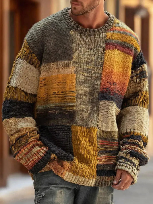 Mann trägt den Rundhalspullover in Erdtönen mit grob gestrickten Patchwork-Feldern, Frontansicht auf einer Straße 1