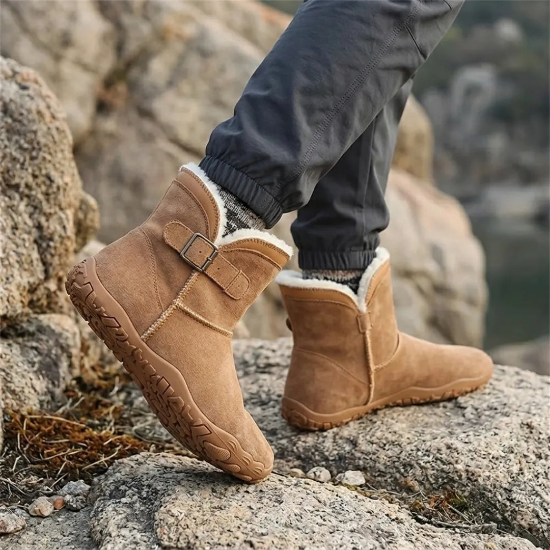 Braune Stiefel mit hellem Fellrand, getragen mit gemusterten Socken auf Felsen mit Blick aufs Wasser 20