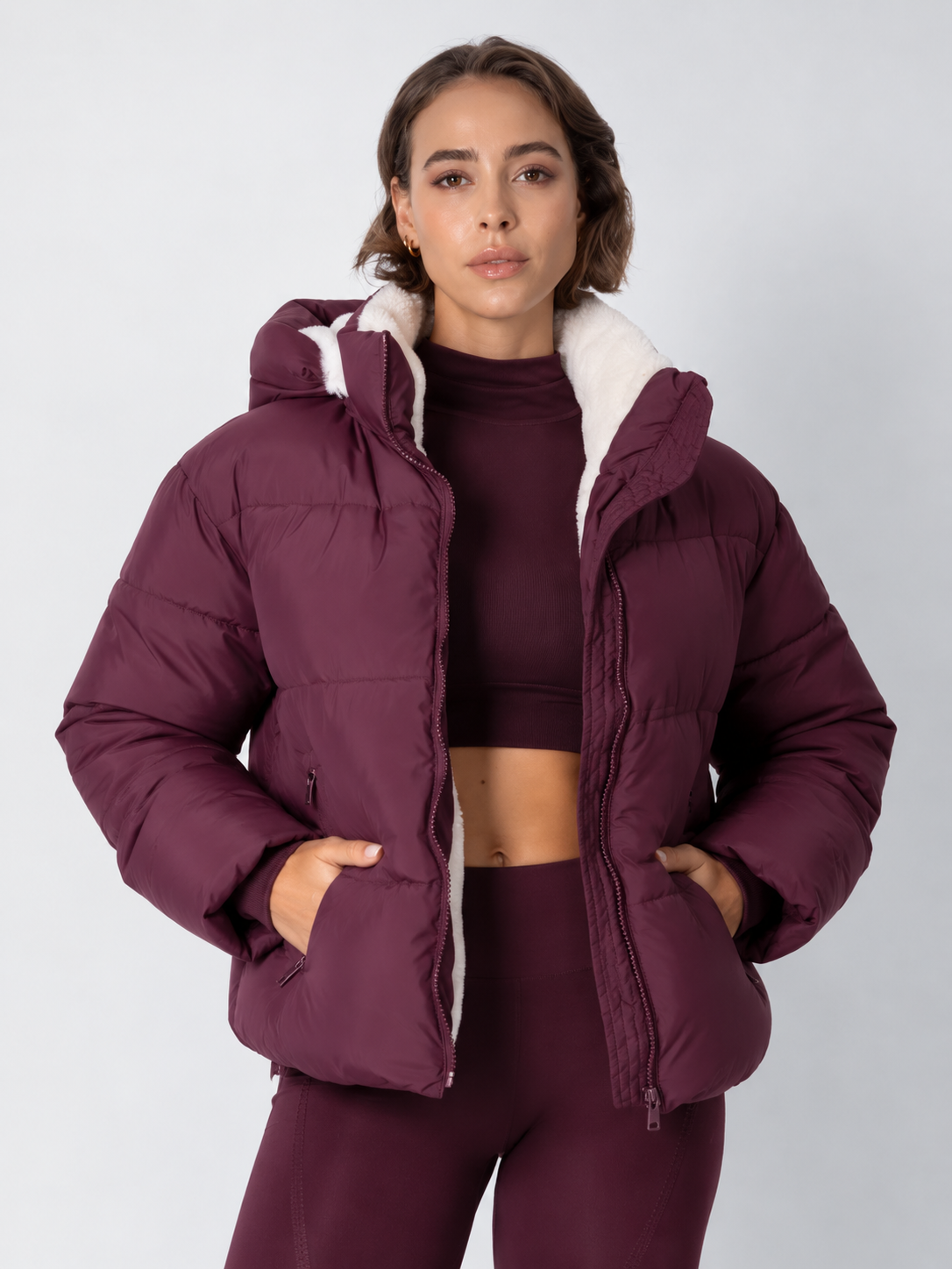 Model in bordeauxroter Steppjacke mit weißem Fleecefutter, kombiniert mit passendem Crop-Top, Frontansicht 16