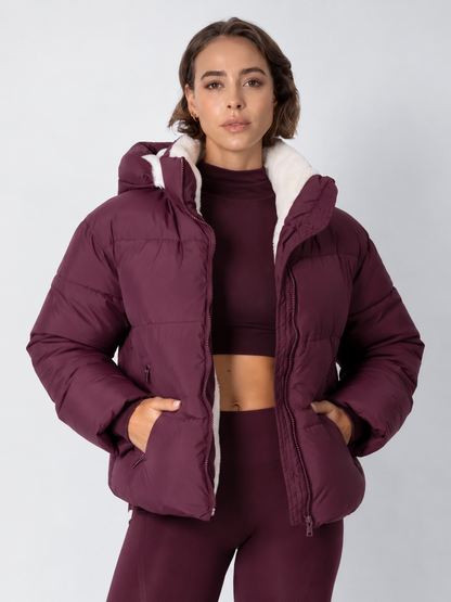 Model in bordeauxroter Steppjacke mit weißem Fleecefutter, kombiniert mit passendem Crop-Top, Frontansicht 16