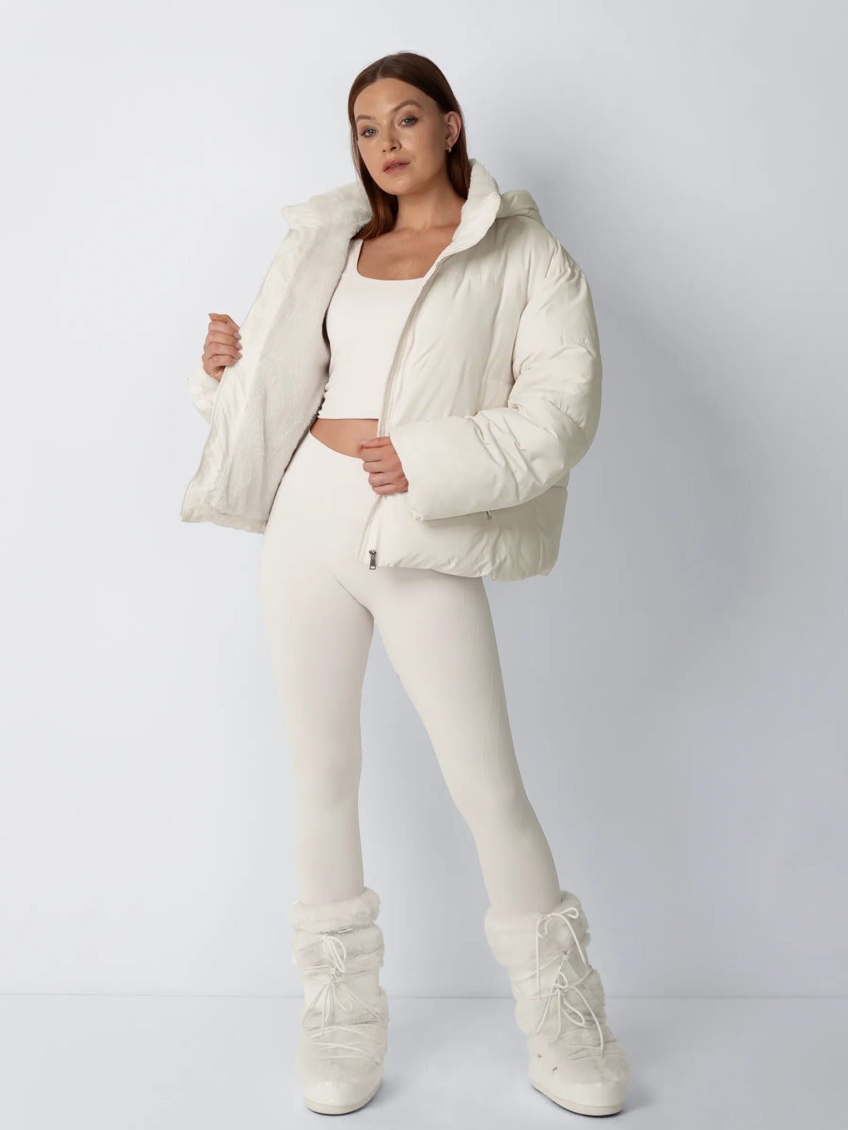 Model in cremeweißer Steppjacke zeigt das flauschige Fleecefutter innen, kombiniert mit Fellstiefeln, Ganzkörperansicht 2
