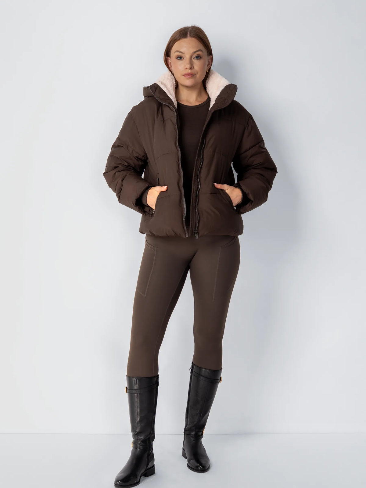 Ganzkörperansicht der braunen Steppjacke mit braunem Outfit und schwarzen Lederstiefeln 15
