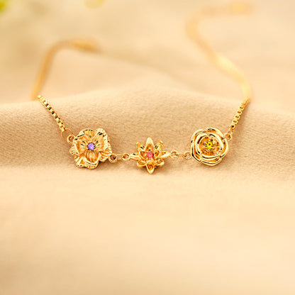 Goldene Blumenanhänger mit violettem, rosafarbenem und gelbgrünem Stein auf weichem beigem Stoff. 14