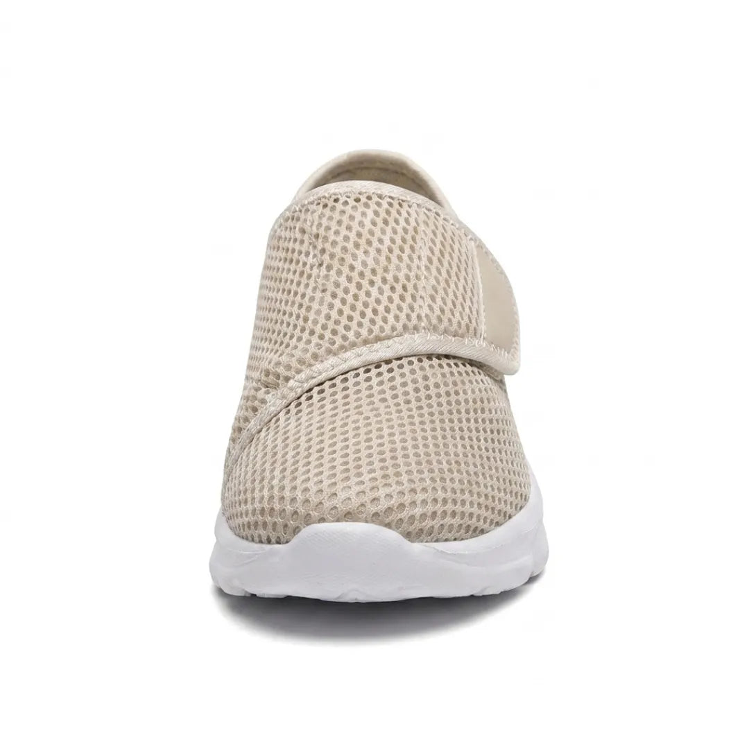 Frontalansicht eines beigen Netzschuhs mit breitem Klettriemen und weißer Sohle, die die geräumige Schuhspitze zeigt. 35