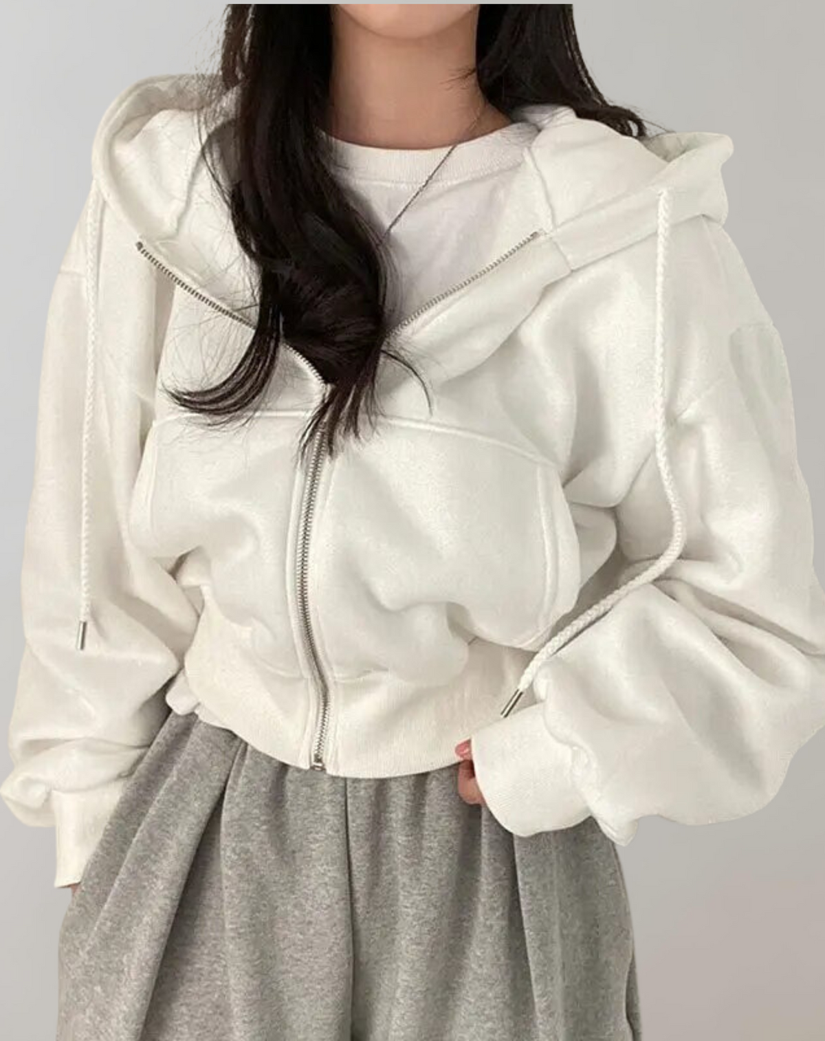 Cremeweißer Damen-Hoodie mit silbernem Reißverschluss und geflochtenen Kordeln.