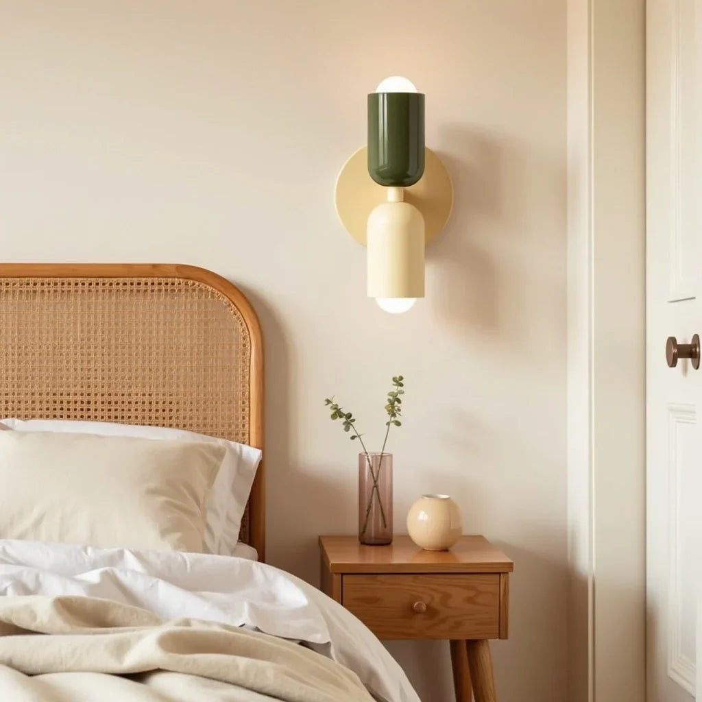 Wandlampe in Dunkelgrün und Creme neben einem Rattan-Bettkopfteil, über einem Holz-Nachttisch mit Glasvase und runder Keramikkugel. 13