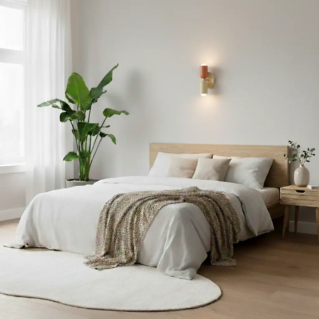 Kleine Wandlampe in Terrakotta und Creme über einem Doppelbett mit weißer Bettwäsche, Pflanze und rundem Teppich im hellen Schlafzimmer. 8