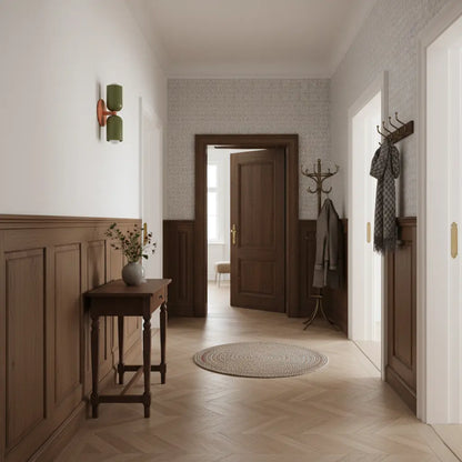Wandlampe in Olivgrün mit orangefarbenem Arm in einem Flur mit Holzvertäfelung, Konsole, Garderobe und Fischgrätparkett. 7