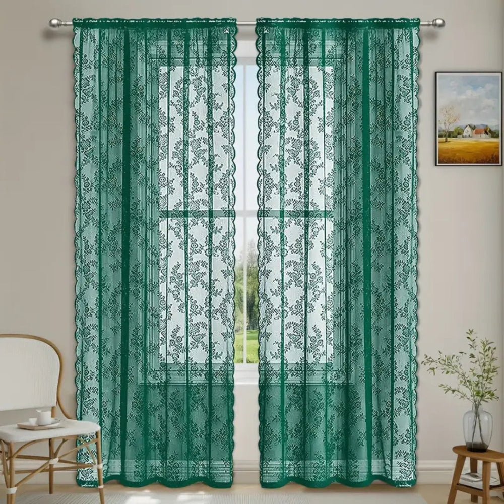 Zwei dunkelgrüne transparente Spitzenvorhänge mit Blumenmuster hängen an einer Stange vor einem Fenster mit Blick ins Grüne. 5