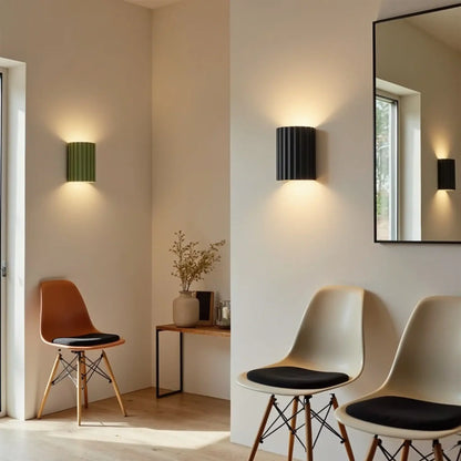 Eine grüne und eine schwarze gerillte Wandlampe in hellem Raum mit Stühlen, Konsole und Spiegel 3