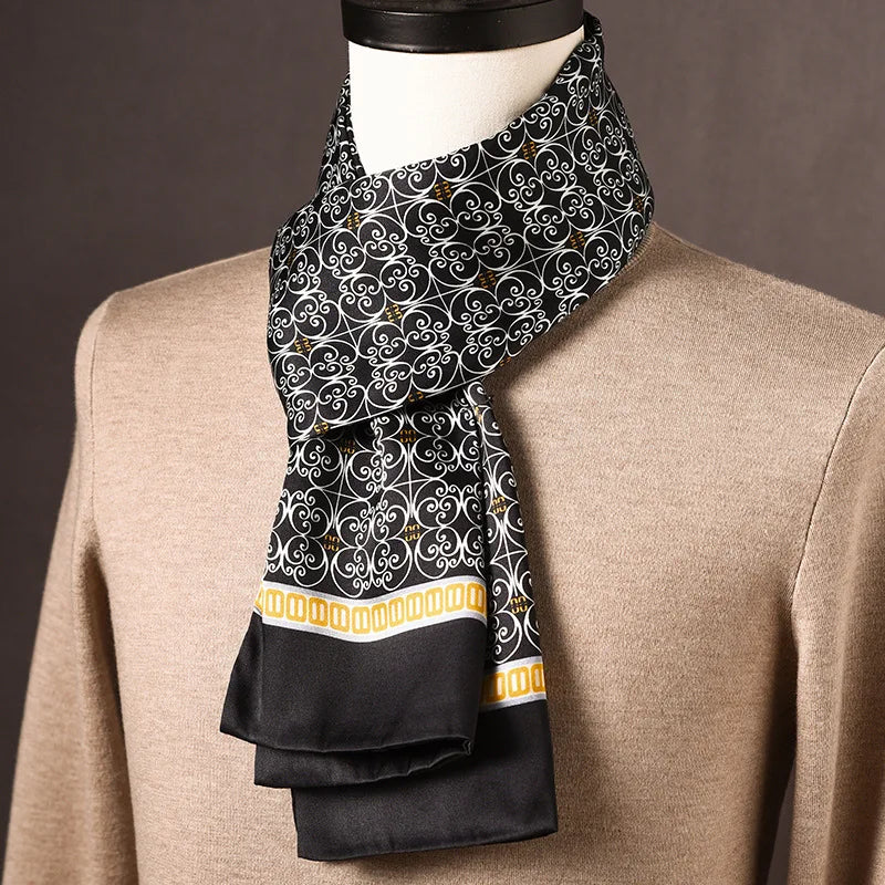 Schwarzer Seidenschal mit weißem Schnörkelmuster und gelber Zierborte, an einer Büste über einem beigen Pullover drapiert. 25